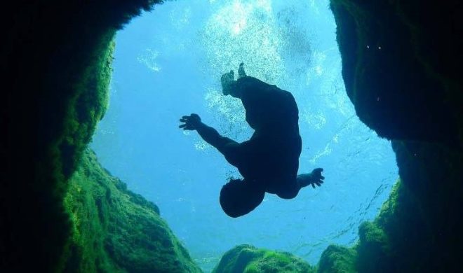A diver sinks into the spring water at Jacobs well