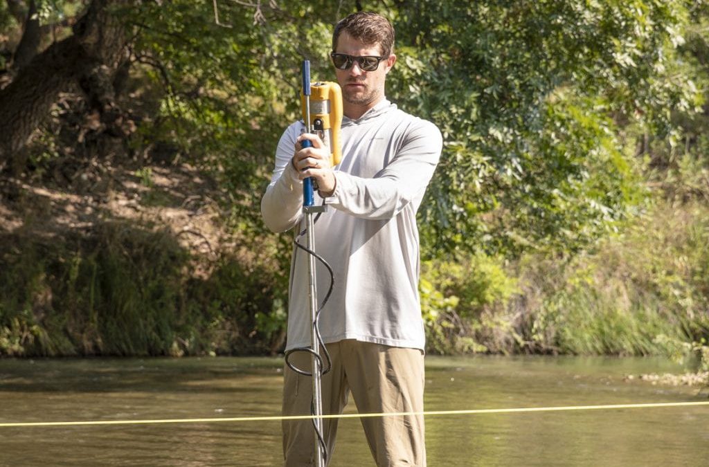 Kyle Garmany stands in calf-high water with a field tool