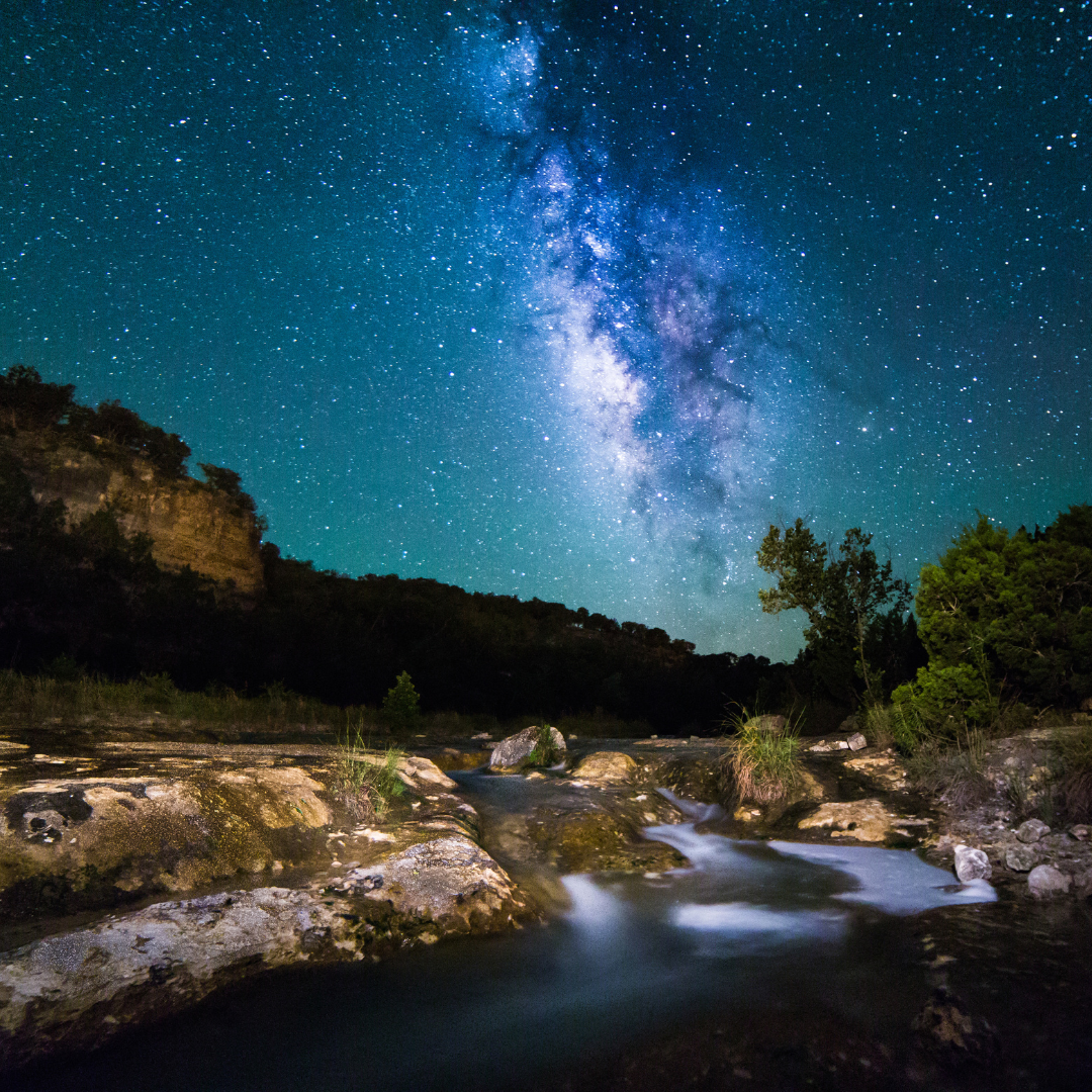 The Milky Way illuminates a brilliant blue, starry sky over a Hill Country river.