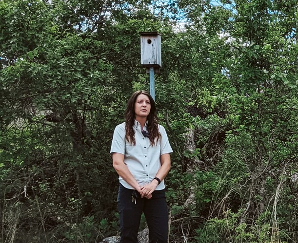 Christina Farrell, an ornithologist, stands in front of a birdhouse