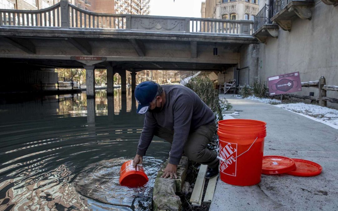 A man taking water from the San Antonio Riverwalk during winter storm for water