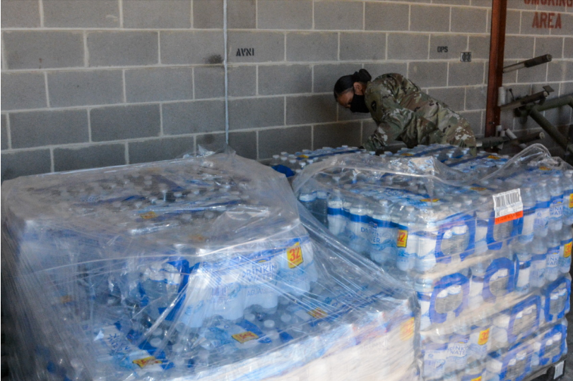 A member of the national guard inspects inventory of water cases ready to be sent out for Winter Storm Uri