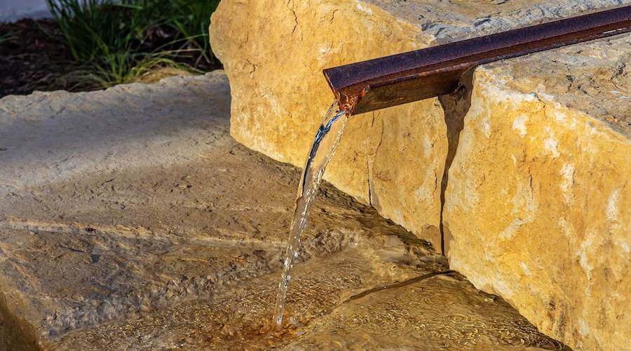 Water runs out of a pipe onto a limestone rock