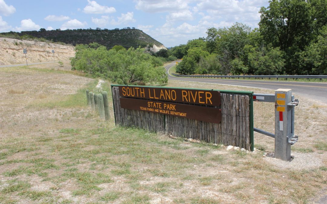 A sign says "South Llano River State Park" with a background of the Hill Country behind it